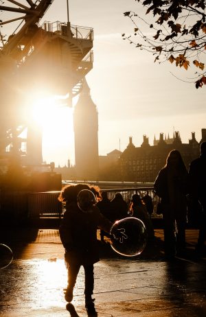 Girl playing with soap bubbles in London captured through street photography.